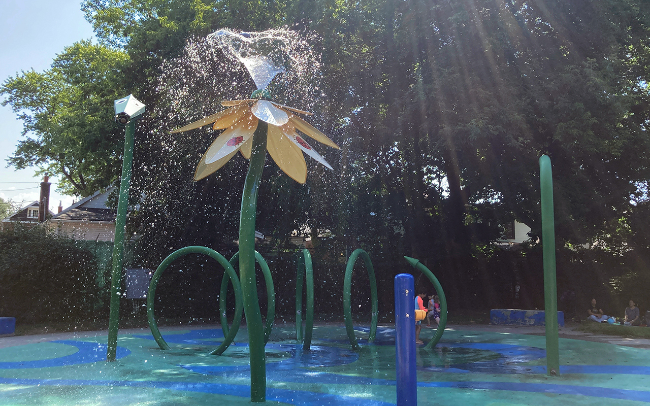 High flower fountain spraying water over a large area of the splash pad.