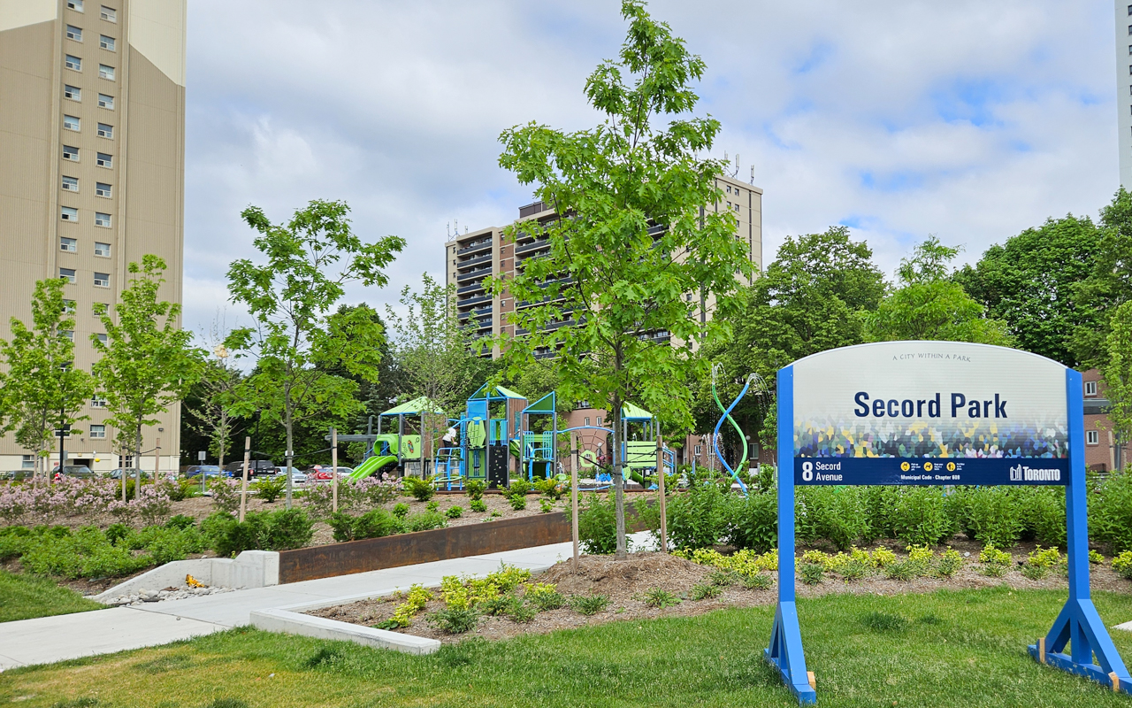 Secord Park sign with pathway leading behind into the playground and splash pad.