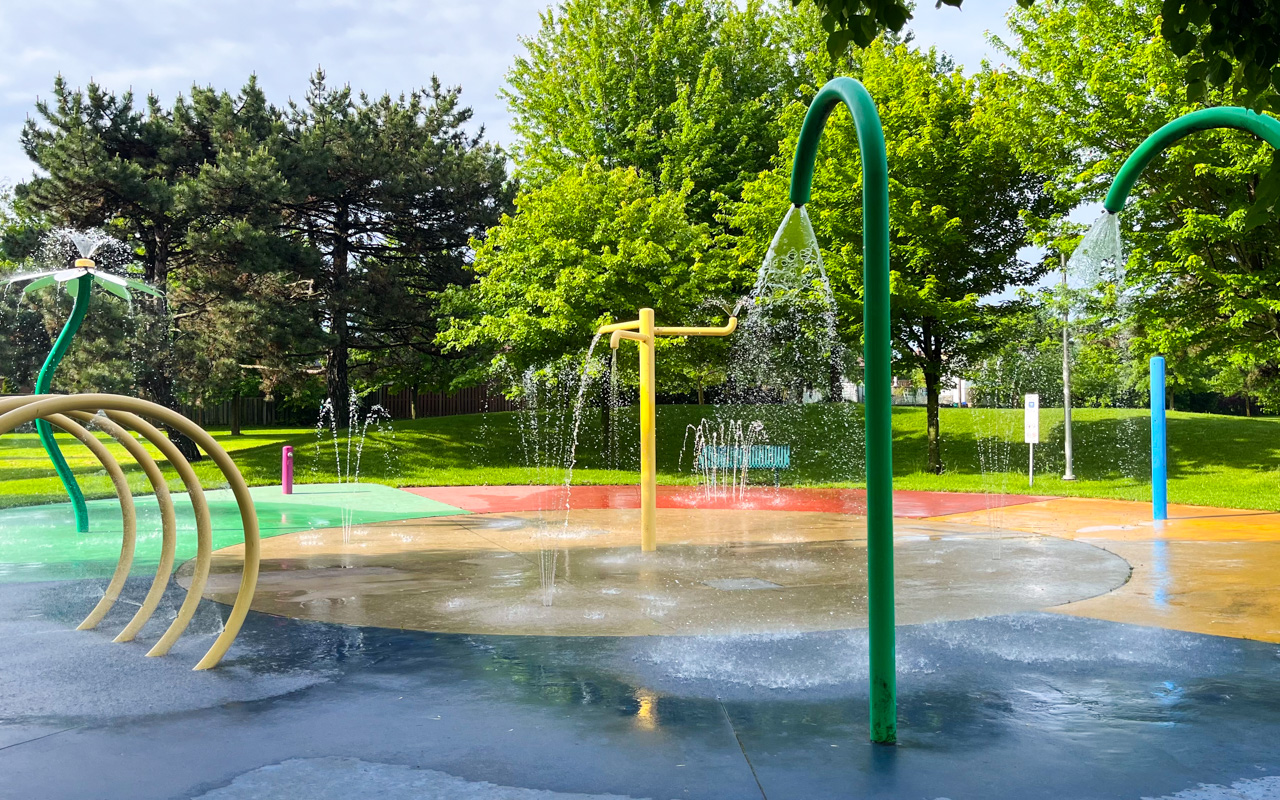 Splash pad surounded by mature trees and bench seating at Dunlop Park.