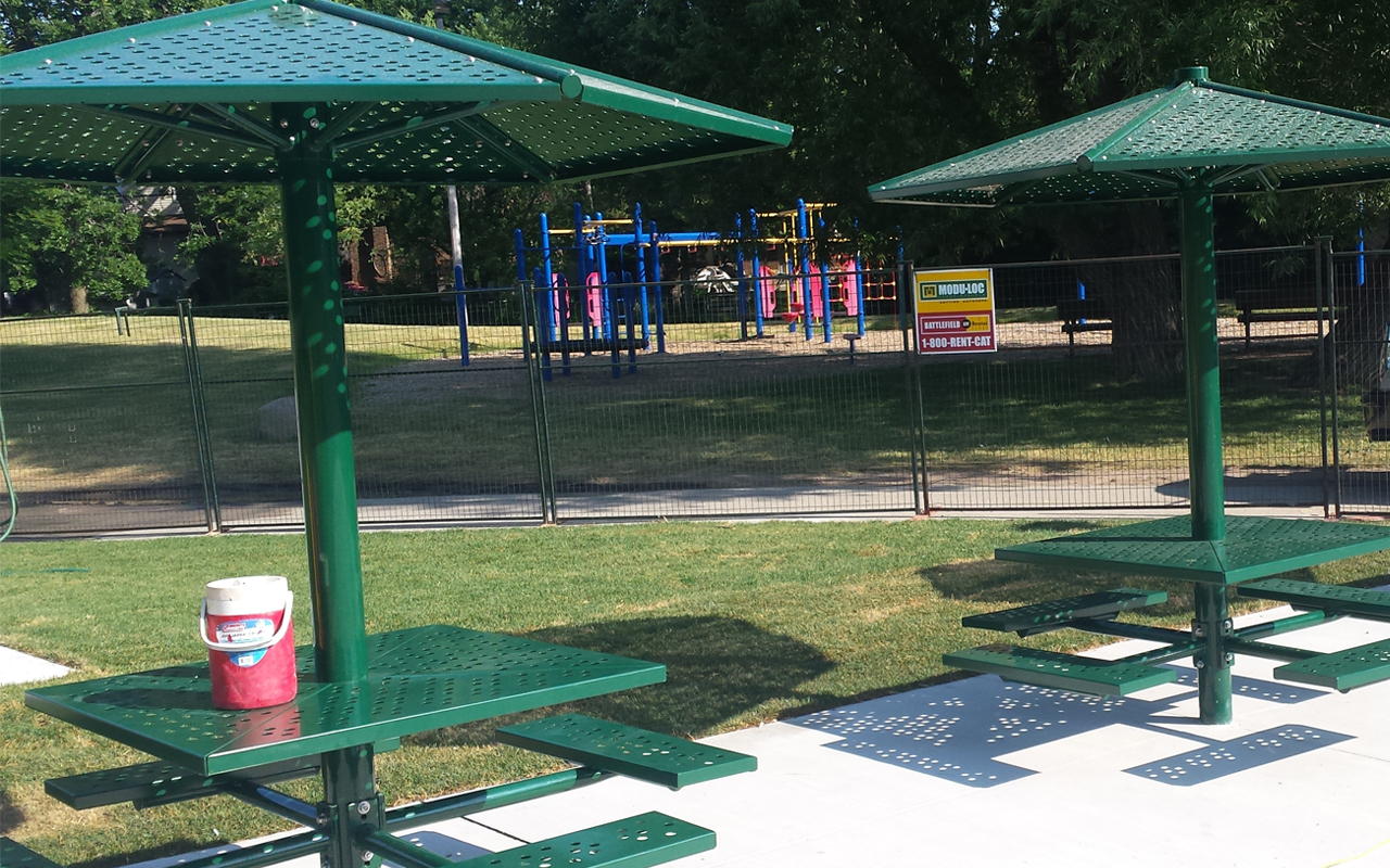 Seating within the Glendora Park splash pad area, and a playground in the background.