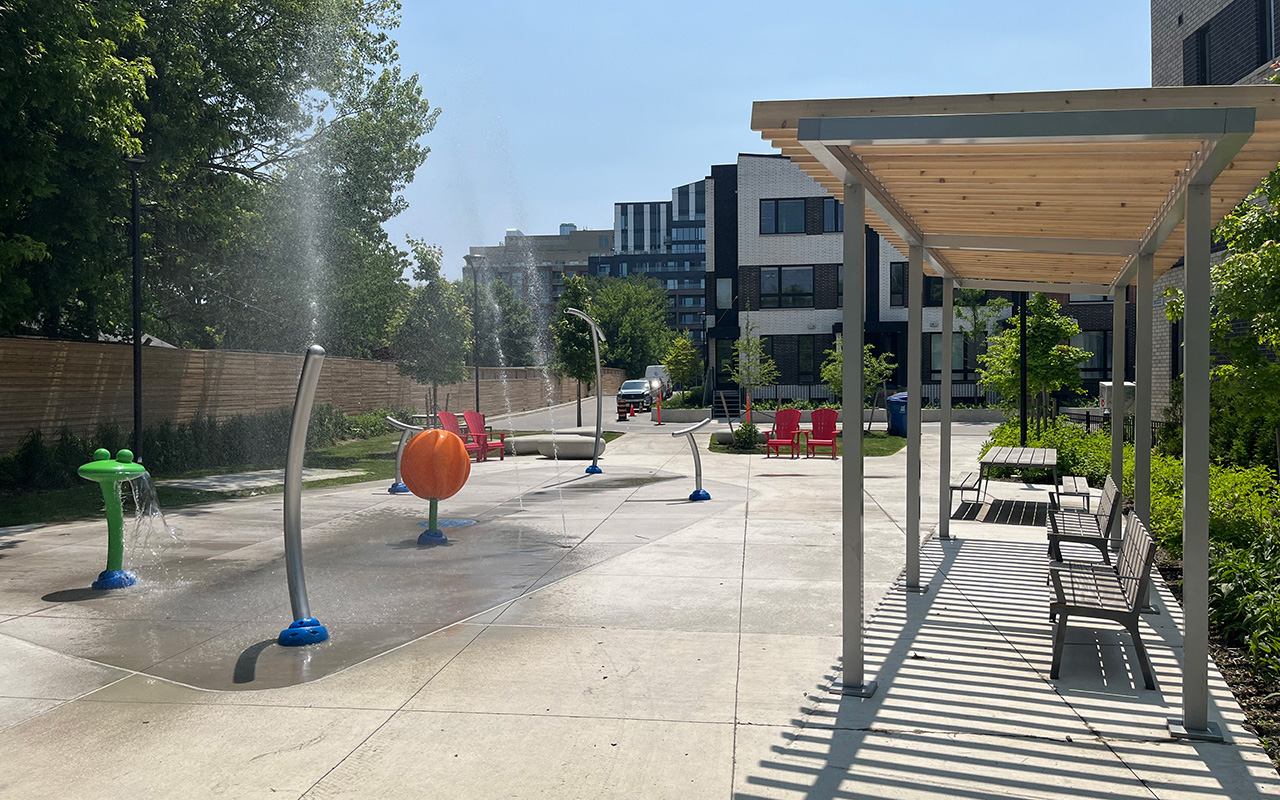Shade structure and seating beside the splash pad at S.A.D.R.A. Park