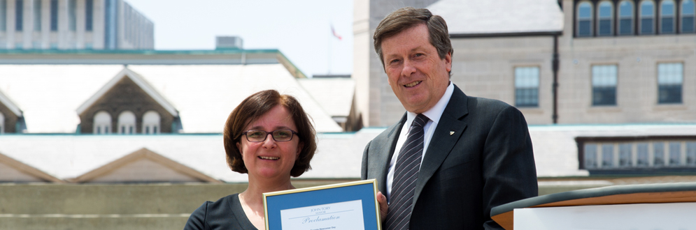 Mayor John Tory presents a framed proclamation to a woman