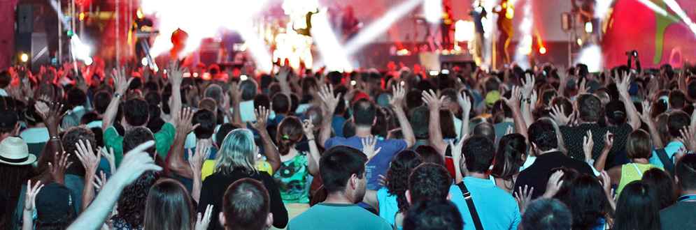 photo of a large crowd dancing in front of a concert stage during a performance