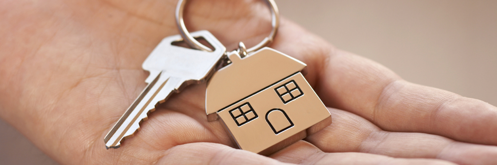 hand holding a key with a keychain in the shape of a house