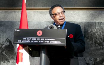 George Elliott Clarke delivering a speech next to a Canadian flag