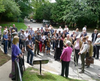Dr. Clarke speaking to a large crowd of people in a park