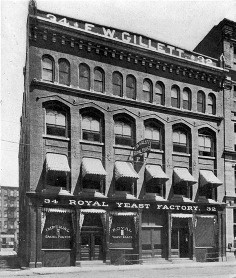 Written across the top of the facade of this four-storey building is: F.W. GILLETT. On the front of the building is written: ROYAL YEAST FACTORY. Lettering on the front display windows says: IMPERIAL BAKING POWDER AND ROYAL YEAST CAKES.