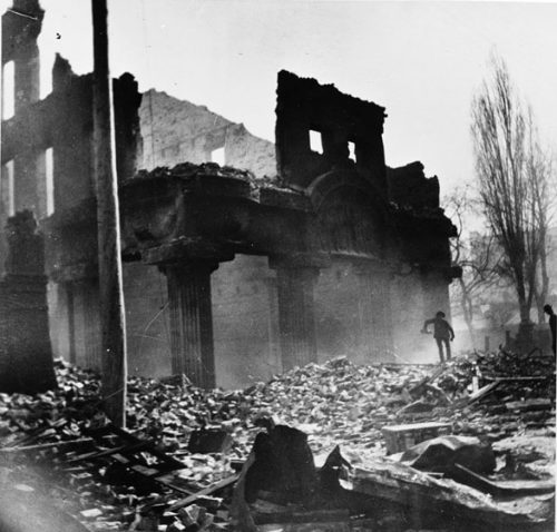 The arch and pillars at the entrance to the Brown Brothers building still stand after the fire. The street in front of the building is covered with bricks and other rubble.