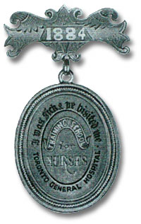 A picutre of an Original blue with black letters Training School for Nurses Pin, 1884