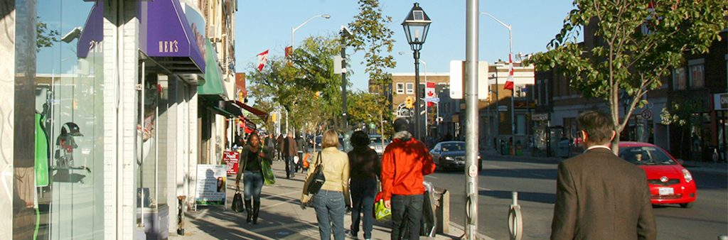 People walking along Bloor street sidewalk next to shop fronts