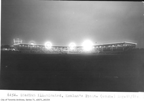 Bright spots of light shine from baseball stadium bleachers.