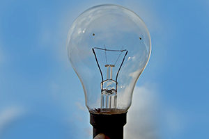 A photo of a light bulb held up to the sky.