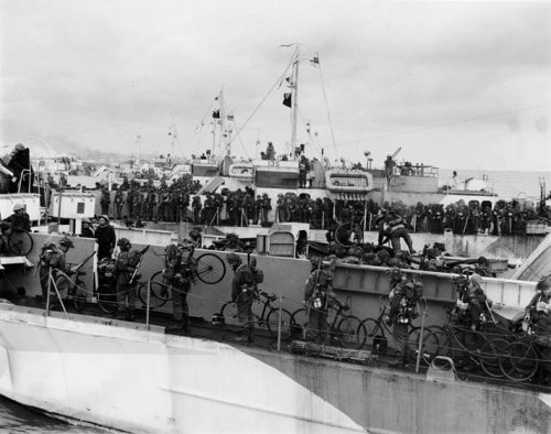 Soldiers holding bicycles line the deck of a ship