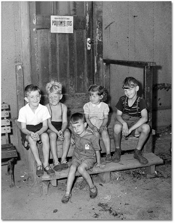 Kids sitting on a step underneath a "quarantine" sign.