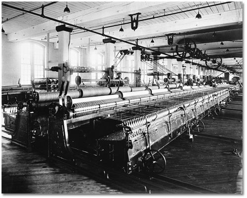 Long automatic looms on a large factory floor lit by big windows.