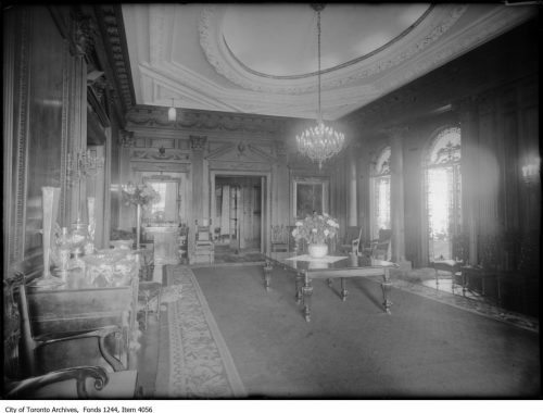 Dining room with heavy wooden furniture and large chandelier.