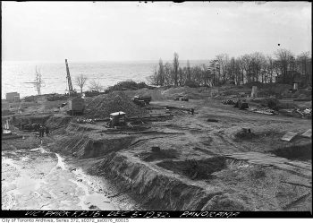 Construction workers and equipment on a cleared area by the lake.