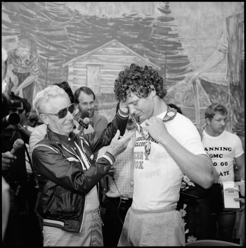 A picture of Terry Fox receiving the mayoral chain from Mayor Harris, Mayor putting the chain around Terry Fox's neck