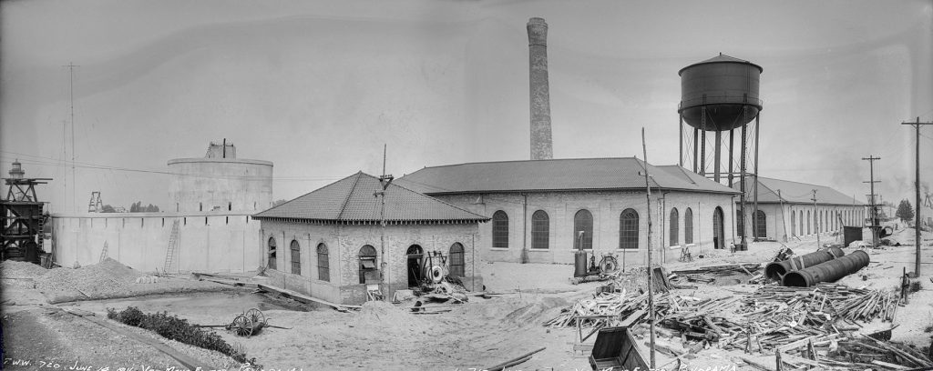 Round concrete structure, long low brick building, and water tower..