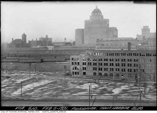 A abandoned brick factory, train tracks and trains, and the tall, broad Royal York Hotel in the background.