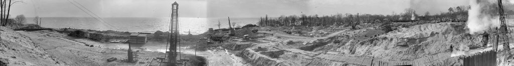 A large, bare, uneven area beside the lake, with construction equipment on it.