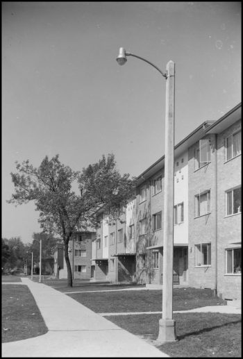 Concrete lamp post outside a row of 1950s townhouses.