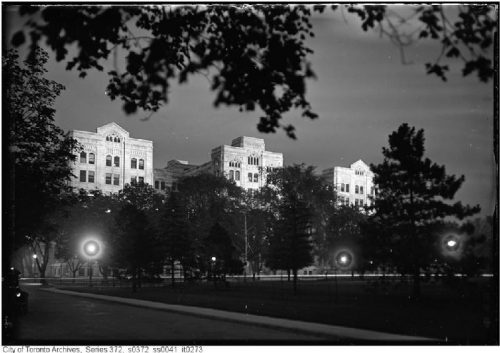 Three wings of a stone building lit up at night.