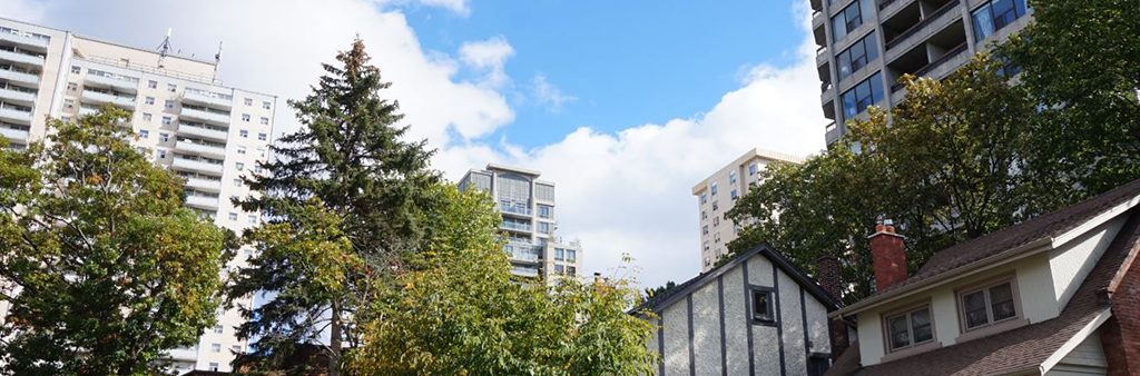 View of early 20th century houses on Gothic Avenue and recent and mid-twentieth century tall buildings on Quebec and High Park Avenue.