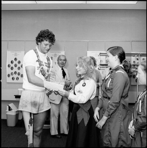 A picture of Terry Fox receiving gifts from two girl guides