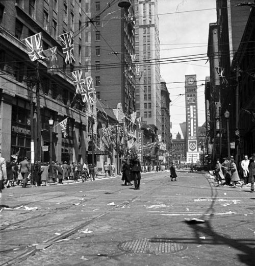 Buildings on Bay Street are covered in Union Jack flags. At the end of the street, Old City Hall is decorated with ads for Victory Bonds.