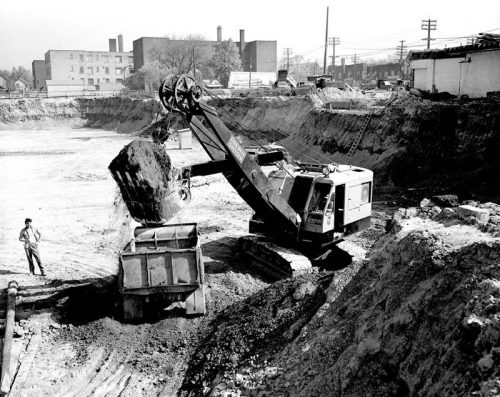 Steam shovel works in large excavation.