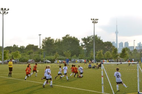 Children playing soccer at the Cherry Beach Sports Fields, CN Tower is in the background 