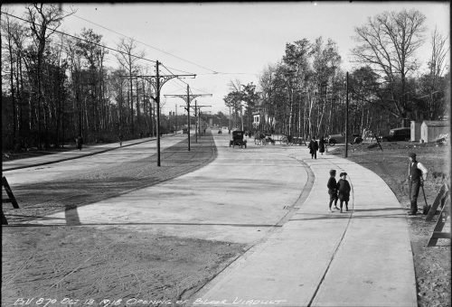 Empty roadbed of viaduct and children on sidewalk.