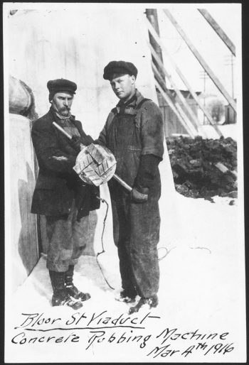 Two men holding a round piece of wood about a foot across.