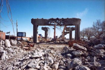Concrete support pillars crumbling and falling down, rubble in the foreground