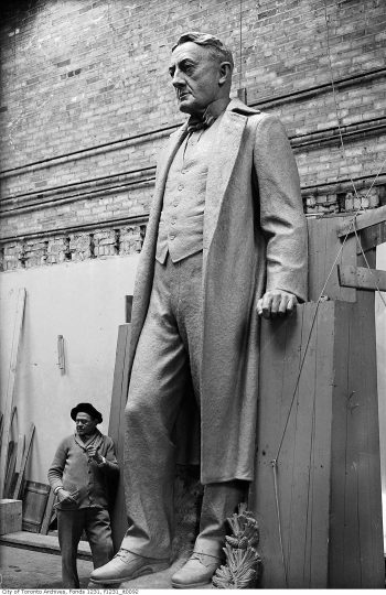 Sculptor stands at foot of large stone man.