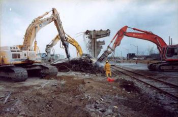 Large jackhammer machines break up a concrete slab on the ground