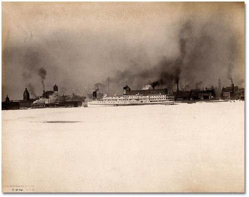 Many buildings have chimneys pouring dark smoke into the air.