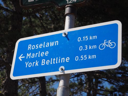 Photograph of a small blue wayfinding sign directing cyclists to nearby roads and trails