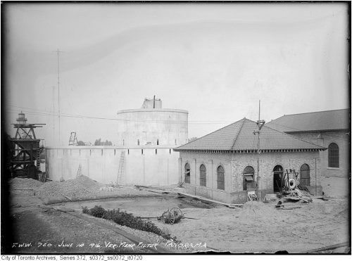 Round concrete structure and low brick building.