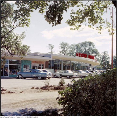 Cars parked in front of a curving strip mall.