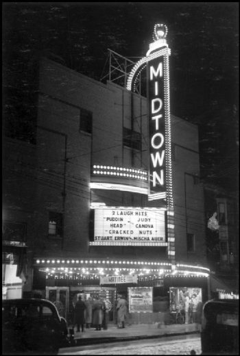 Theatre sign and outside area bright with lights. Movies playing are "Puddin' Head" and "Cracked Nuts."