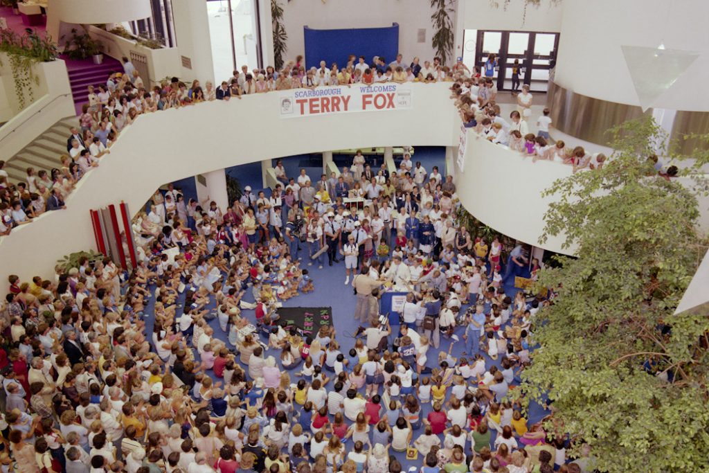 A picture of inside Scarborough Civic Centre of Terry Fox and hundreds of people gathered around