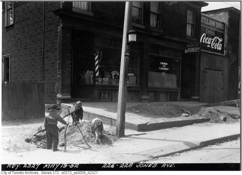 Children play in a pile of excavated dirt underneath a lantern on a hydro pole.