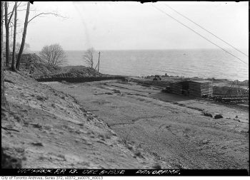 Construction materials stacked on a bare area near the lake.