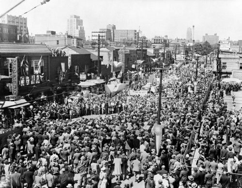 The street is lined with Chinese businesses and crowded with people.