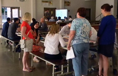 Photo of someone writing comments down at the June 2016 Keele Finch Plus consultation. A presentation is taking place in the background.