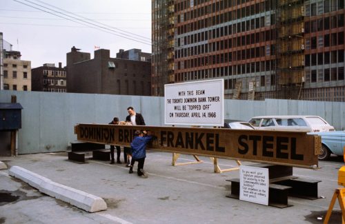 People sign a large steel girder propped up on blocks.