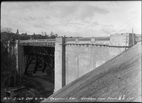 Concrete bridge with arched metal supports.