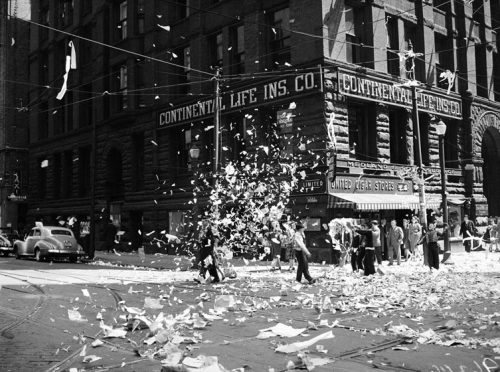 Pieces of paper fill the air above a city intersection.